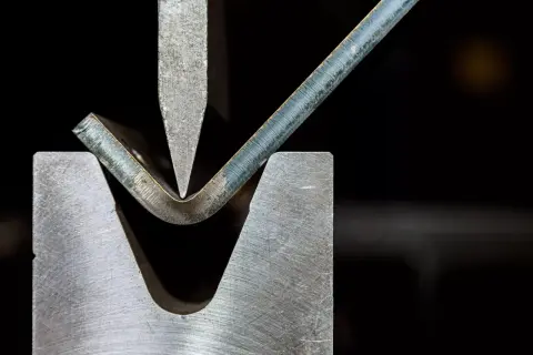 Metal sheet being bent by a press brake tool.