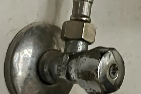 Metalowy zawór wody z uchwytem i śrubą.