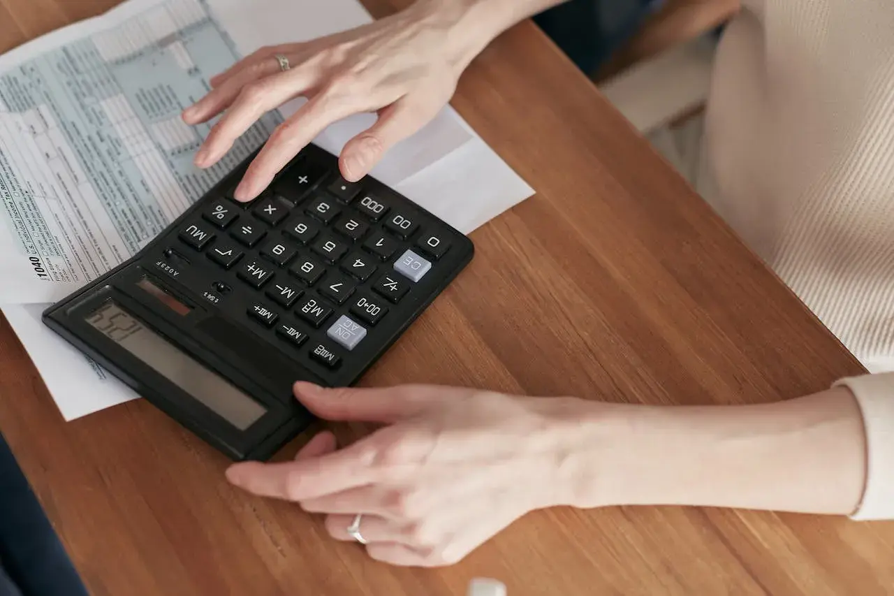 Kobieta liczy na kalkulatorze, szukając informacji, jak zrezygnować z opłaty handlowej Tauron.
