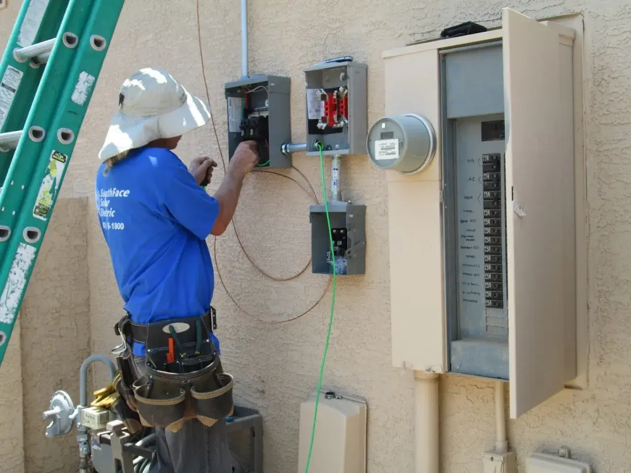 Elektryk pracuje przy skrzynce elektrycznej, podłączając przewody. To kluczowy etap instalacji, który zapewni odpowiednią moc przyłączeniową.