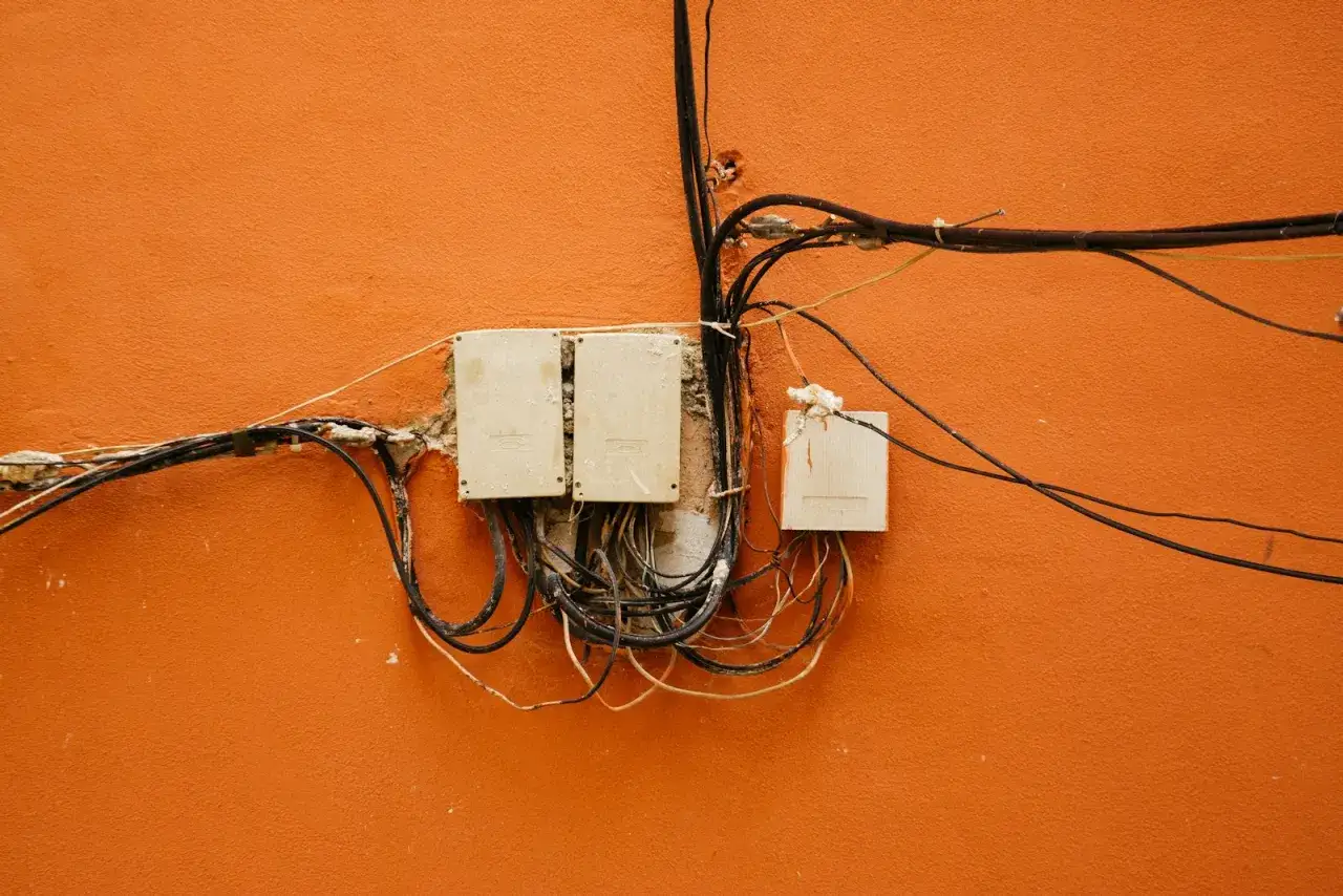 Plątanina kabli i trzy białe puszki na pomarańczowej ścianie. To miejsce, gdzie dba się o uziemienie instalacji elektrycznej.